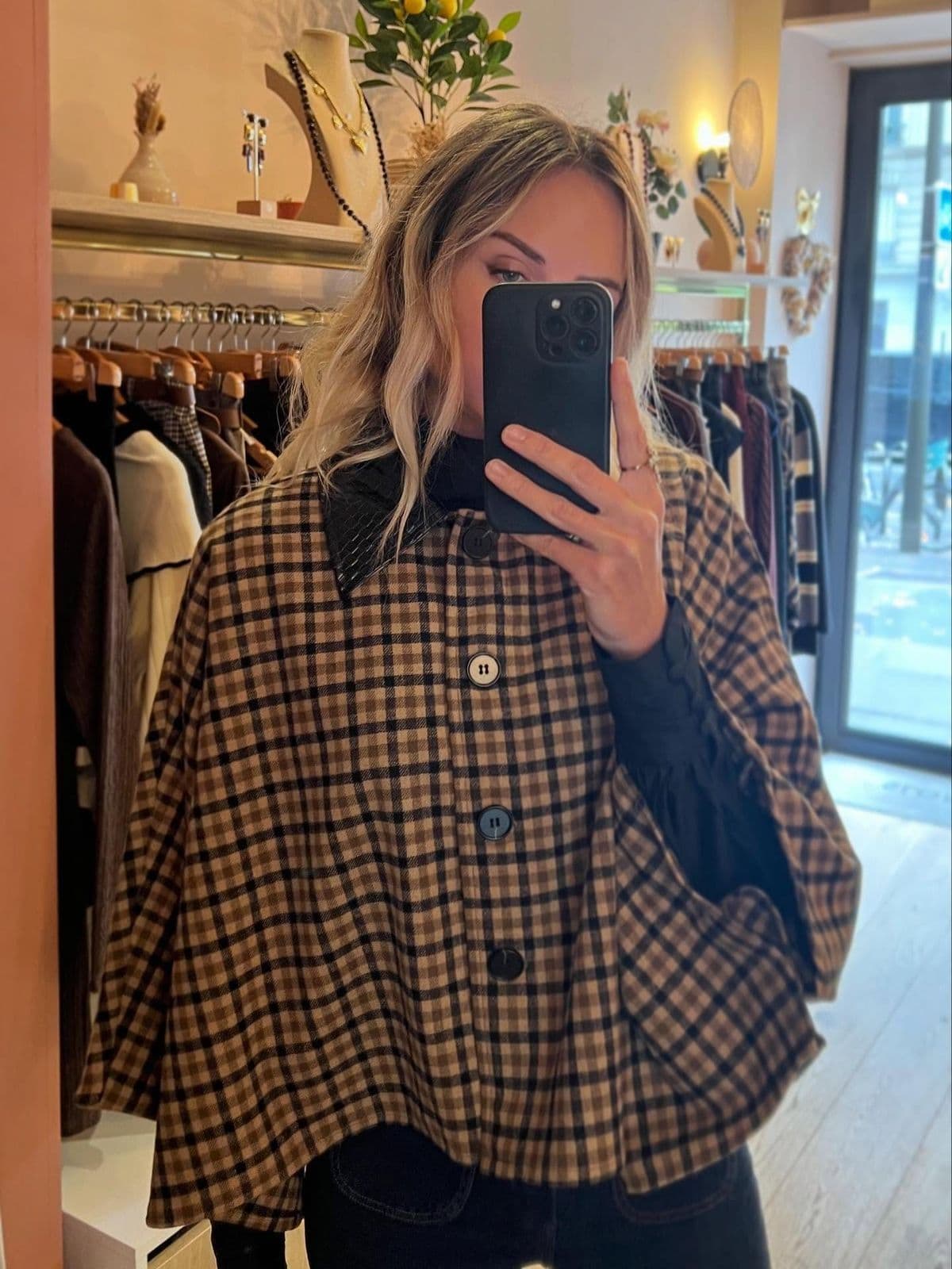 Cape à carreaux essayée devant le miroir de la boutique